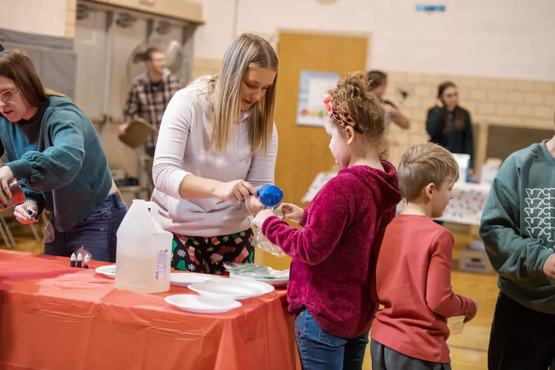 Student teacher helps students with an experiment at a STEAM event